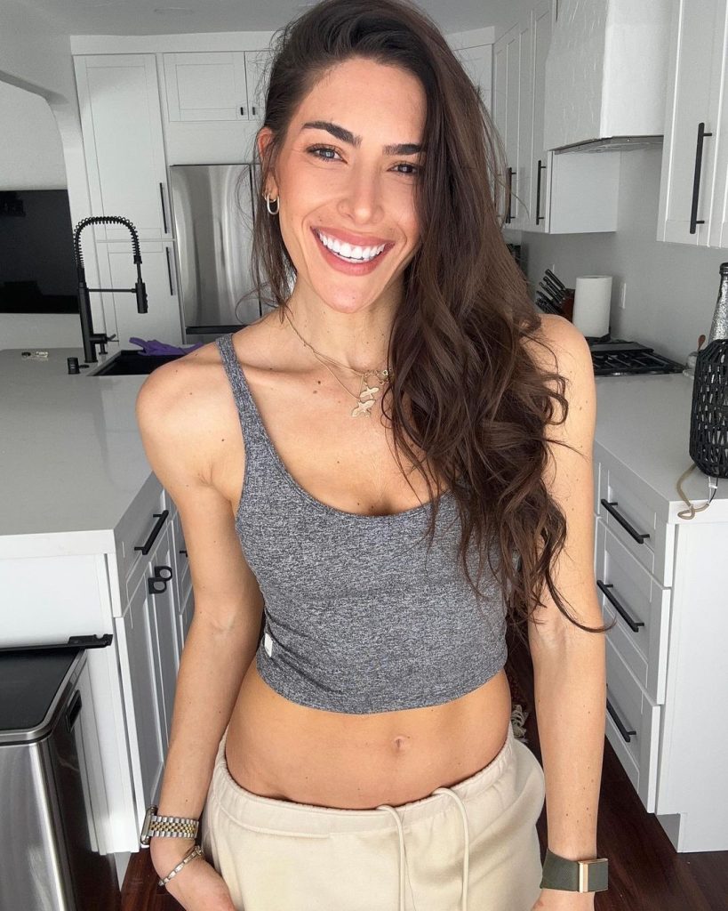 Nikki wearing grey tank top and off white bottoms.